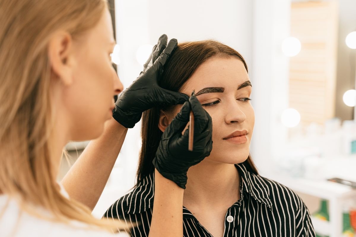 A brow artist mapping and defining a brow shape on a client in the studio